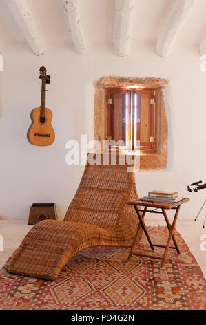 Fauteuil inclinable et guitare acoustique sur le mur Banque D'Images