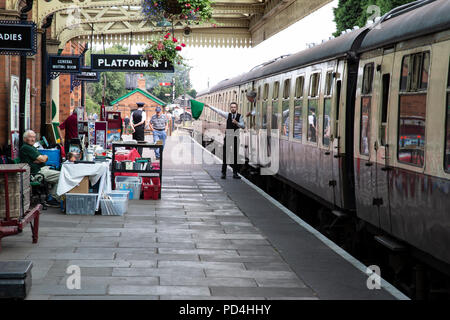 Garde de fer sur le Great Central Railway heritage line qui agitait un drapeau vert pour signaler 'tout de suite' pour le pilote du moteur à Loughborough gare Banque D'Images