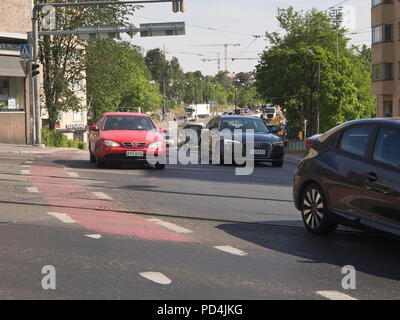 Le trafic d'Helsinki en Finlande, une intersection achalandée entre Mannerheimintie et Nordenskiöldinkatu par les voitures, les voies de tram et une piste cyclable goudronnée rouge Banque D'Images