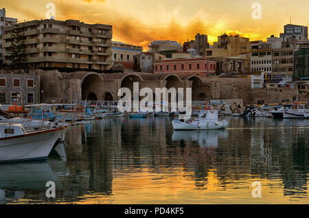 Héraklion, Crète / Grèce. Coucher de soleil sur le vieux port avec les chantiers navals de Venise à Héraklion. Pêcheur avec son bateau de pêche traditionnel Banque D'Images