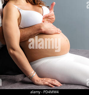 Close up de détail de l'homme faisant mains massage femme enceinte sur l'abdomen. Banque D'Images