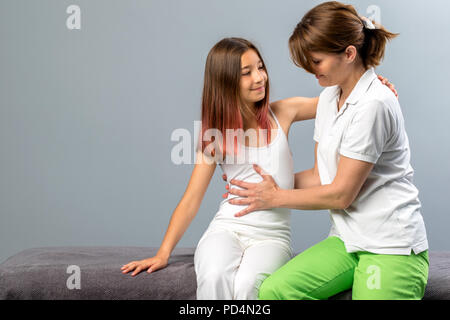 Portrait de l'enfant à un traitement ostéopathique session. Physiothérapeute femelle manipulation thorax de petite fille. Banque D'Images