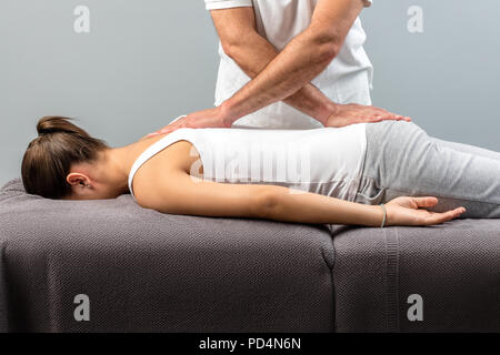 Physiothérapeute de manipulation faire massage le jeune femme. Banque D'Images