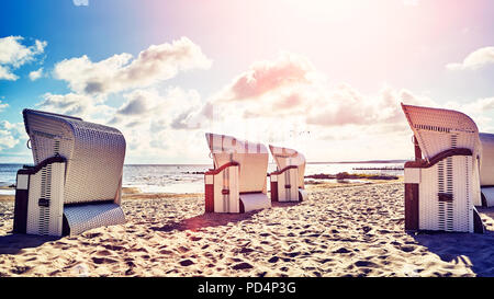 Retro photo stylisée de l'osier panier à capuchon de chaises sur une plage au coucher du soleil, vacances d'concept. Banque D'Images