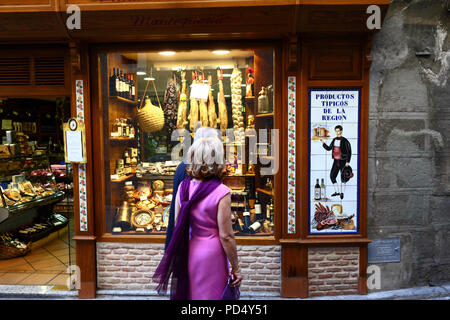 Couple à la recherche d'une fenêtre de magasin qui vend des produits locaux typiques et de jambons, Toledo, Castille-La Manche, Espagne Banque D'Images