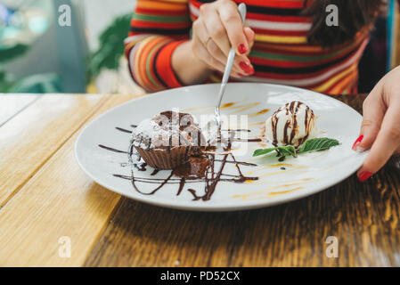 Young adult woman eating fondant au chocolat dans le café. Banque D'Images