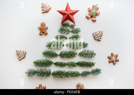 Idée créative pour Noël ou Nouvel An thème. Un arbre de Noël à partir de branches d'épinette et une étoile sur le dessus. À proximité se trouvent gingerbread cookies. Concept de célébration. Banque D'Images