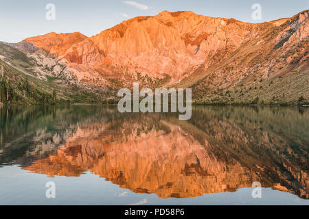 Sunrise jette une lumière dorée sur des pics de montagne reflète dans les eaux calmes d'un lac alpin - Convict Lake dans les montagnes de la Sierra Nevada de Californie Banque D'Images