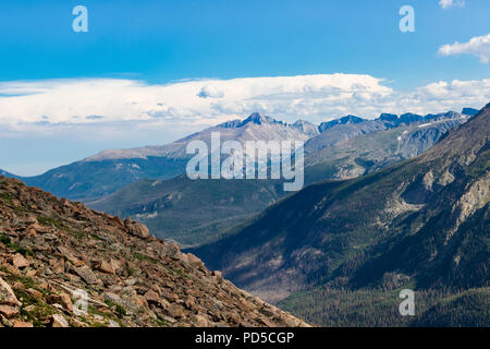 Rockies du Colorado ensoleillée, avec Rocky hill, avant gauche de bleu-gris spectaculaires montagnes derrière, avec des plantes vertes ci-dessous. Ciel bleu et nuages au-dessus Banque D'Images