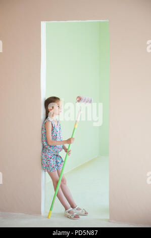 Belle petite fille aux mains en rouleaux à peindre en couleur nouveau prix dans l'intérieur de la chambre Banque D'Images