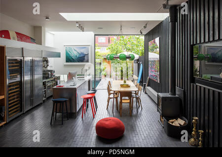 Maison de famille en plan ouvert avec des murs revêtus de bois et poêle à bois. La lampe verte est conçu par Andy Martin Banque D'Images