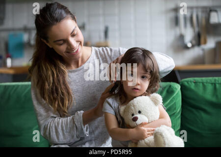 Prendre soin mère enfant brossage de cheveux filles sitting on sofa Banque D'Images