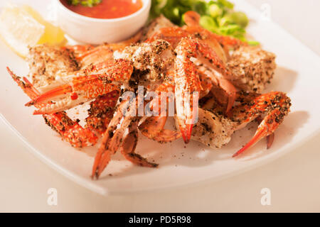 Pinces de crabe en sauce poivre sur une plaque blanche Banque D'Images