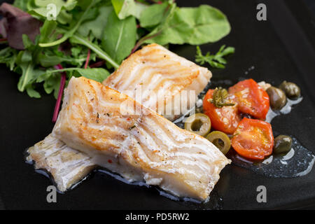 Filets de morue aux olives et câpres sur la plaque noire / cuisine Méditerranéenne Banque D'Images