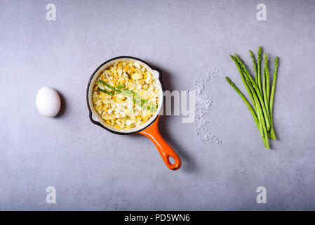 Petit déjeuner maison, pan fried d'œufs brouillés aux asperges sur gris de table, vue ci-dessus Banque D'Images