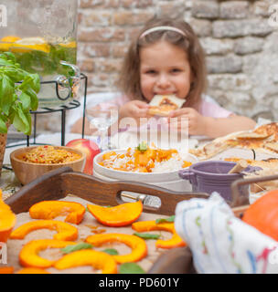 La petite fille mange de la tarte. Dîner familial dans la cour extérieure. Légumes et fruits d'automne sur la table. Table à manger . Un lieu spécial pour le texte Banque D'Images