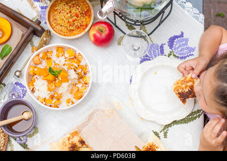 La petite fille mange de la tarte. Dîner familial dans la cour extérieure. Légumes et fruits d'automne sur la table. Vue sur le dessus de la table à manger. Un lieu spécial pour le texte Banque D'Images