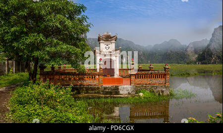 Pagode dans un champ de riz avec les montagnes de calcaire dans le fond recouvert de brouillard Banque D'Images