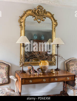 Miroir en bois doré au-dessus de la console avec paire de feux et des chaises Banque D'Images