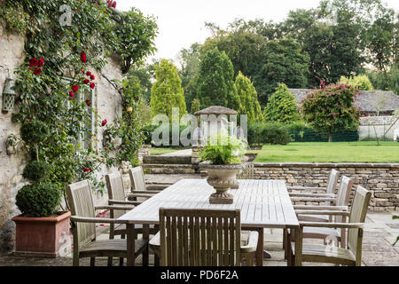 Table et chaises sur terrasse avec rosier grimpant Banque D'Images