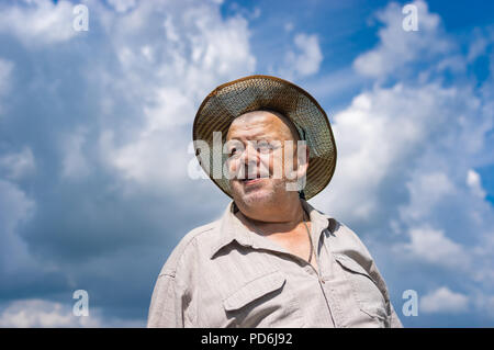 Beau portrait de senior ukrainien agriculteur en chapeau de paille contre blue cloudy sky Banque D'Images