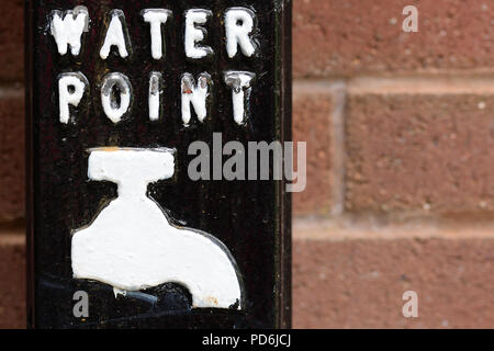 Panneau du point d'eau peinture blanche avec texte et appuyez sur robinet sur fond noir sur mur de brique rouge. Les questions de l'eau de l'environnement concept Banque D'Images