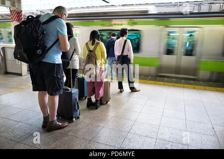 L'île de Honshu, Japon, Tokyo, Kanto, personnes waitng un train sur une plate-forme. Banque D'Images