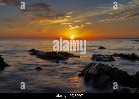 Clapotis de la mer autour des roches au coucher du soleil Banque D'Images