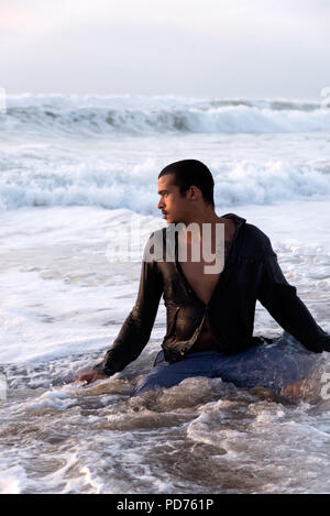 Beau jeune homme multi-ethnique dans le surf sur la plage Banque D'Images