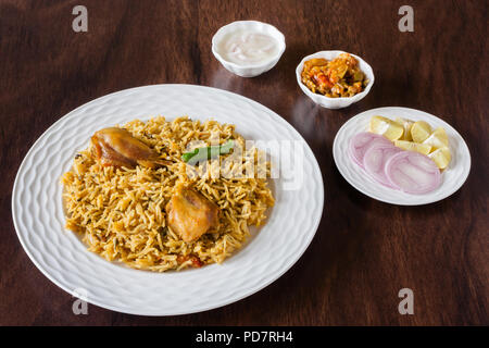 Vue aérienne de la partie supérieure de délicieux biryani poulet indien servi avec des côtés, salade (raita) et de la sauce. Lumière naturelle utilisée. Banque D'Images