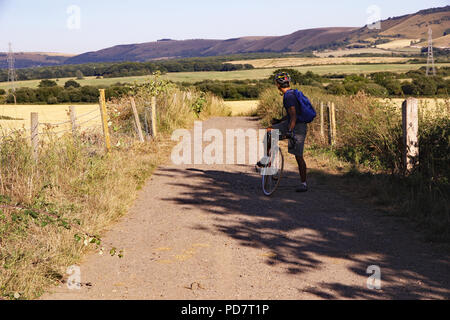 Un cycliste regarde en arrière le long du sentier et bridleway Downs lien vers les South Downs collines au loin sur une chaude soirée d'été. Près de vill Banque D'Images