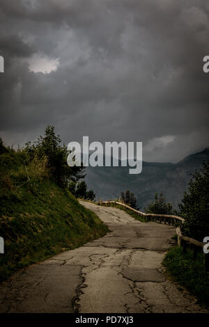 Moody shot d'une liquidation route alpine de sous un ciel sombre et redoutable juste avant une tempête majeure Banque D'Images