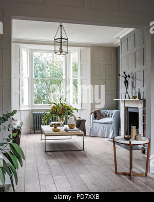 Table basse en bois et métal de Albrissi dans salon avec lambris et frotté de parquet. Le petit fauteuil est recouvert de , fr Banque D'Images