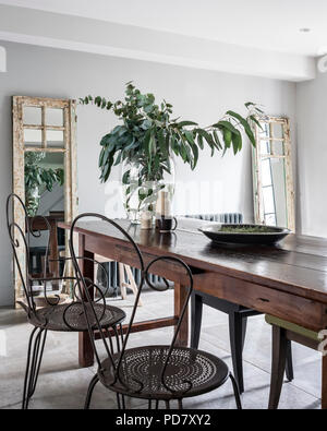 Vintage metal chaises et d'une paire de Philippe Hurel tabourets autour d'une table en bois dans le quartier chic de cuisine avec poêle à bois Banque D'Images