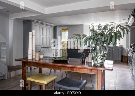 Vintage metal chaises et d'une paire de Philippe Hurel tabourets autour d'une table en bois dans le quartier chic de Martin Moore cuisine avec cuisinière Lacanche et sols en pierre de F Banque D'Images