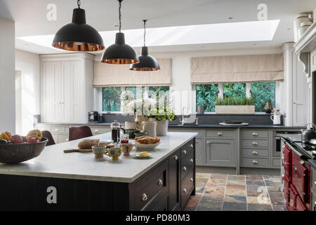 L'île de cuisine sur mesure par Thomas Ford & Sons est peint en brun Tanner par Farrow & Ball. Pendentif style industriel suspendu au-dessus de feux Banque D'Images