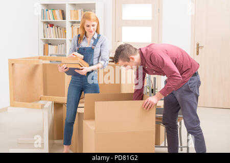 Happy young couple unpacking boxes dans leur nouvelle maison Banque D'Images