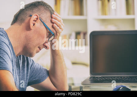 L'homme indépendant sur le lieu de travail avec maux de tête tenait la tête sur les mains. La surcharge de travail, erreur, stress et dépression concept Banque D'Images