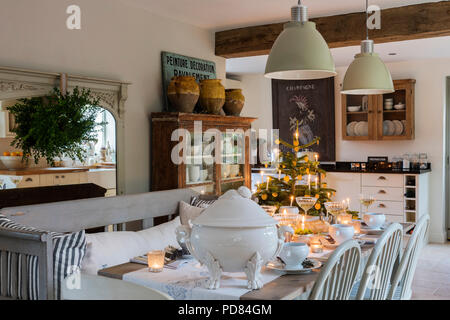 Vintage french panneau en bois au-dessus de l'Aga cuisine / salle à manger avec grande poignée de lumières, de grands pots de confit de jaune. La table est mise et chandelles fo Banque D'Images