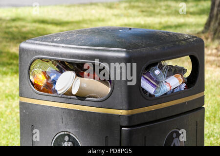 Poubelle débordant de déchets en plastique et en carton non recyclé dans un centre-ville UK. Banque D'Images