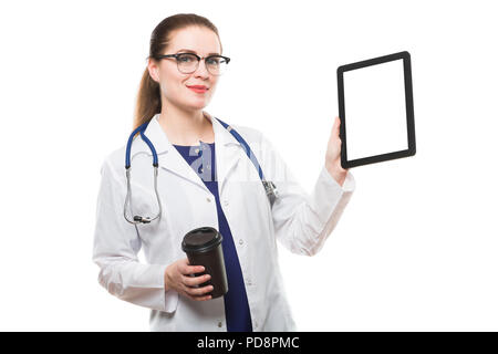 Jolie brunette caucasien confident female doctor standing in office avec tasse de café montrant comprimé dans ses mains sur fond blanc Banque D'Images