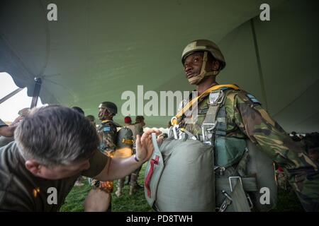Un parachutiste Botswana attend comme une armée américaine Jumpmaster vérifie son parachute avant un saut au cours de l'Université de Leapfest Rhode Island, West Kingston, R.I. Le 5 août 2018, 5 août 2018. Est le plus grand, le Leapfest plus ancien international, de formation en parachutisme en ligne statique de la concurrence et de l'événement organisé par le 56e commandement de troupes, la Garde nationale de Rhode Island pour promouvoir des techniques de niveau et l'esprit de corps au sein de la communauté dans l'internationale. (U.S. Photo de l'armée par le Sgt. Josephine Carlson). () Banque D'Images