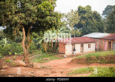 Boutiques et maisons bordent la route d'une petite ville rurale dans le district de Mukono, en Ouganda. Banque D'Images