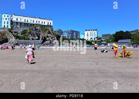 Tenby, Pembrokeshire, Pays de Galles, Royaume-Uni. Le 26 juillet 2018. Les vacanciers appréciant le château plage à marée basse avec des sauveteurs et château à droite à Banque D'Images