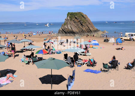 Tenby, Pembrokeshire, Pays de Galles, Royaume-Uni. Le 26 juillet 2018. Les vacanciers profitant de la plage du nord avec l'emblématique Goscar rock sur le rivage à marée basse en Banque D'Images