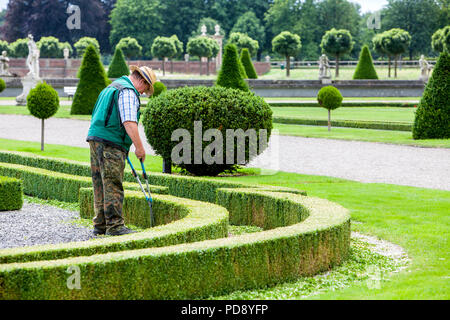 La coupe jardinier au bas des haies de buis à douves Nordkirchen Palace, Allemagne Banque D'Images