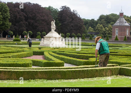 La coupe jardinier au bas des haies de buis à douves Nordkirchen Palace, Allemagne Banque D'Images