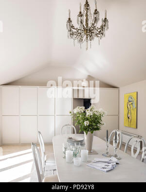 Lustre en verre ancien salle à manger contemporaine de style suédois avec des chaises et une table peints. Un filtre en coin James artwork est suspendu sur le mur. Le tableau a Banque D'Images