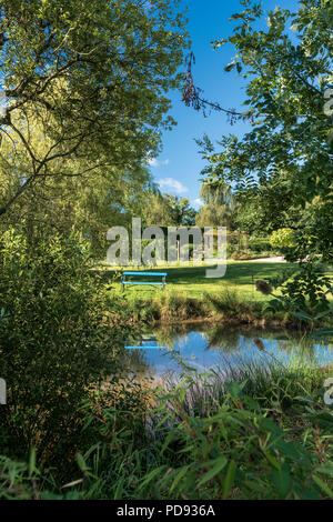 Banc avec vue sur le jardin pittoresque étang dans un jardin anglais Banque D'Images