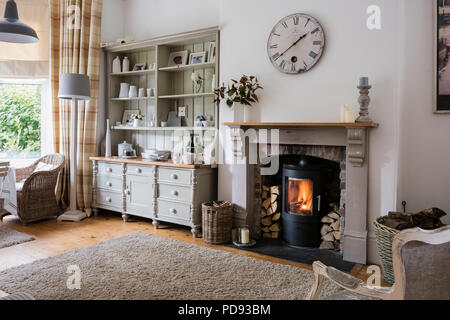 Grand buffet en salle de petit-déjeuner confortable plan ouvert avec horloge murale, poêle à bois et de chaises en osier Banque D'Images